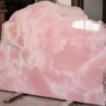 Pink onyx Large natural pink onyx stone block with polished surface, soft rose-pink tones, white mineral patterns and translucent texture