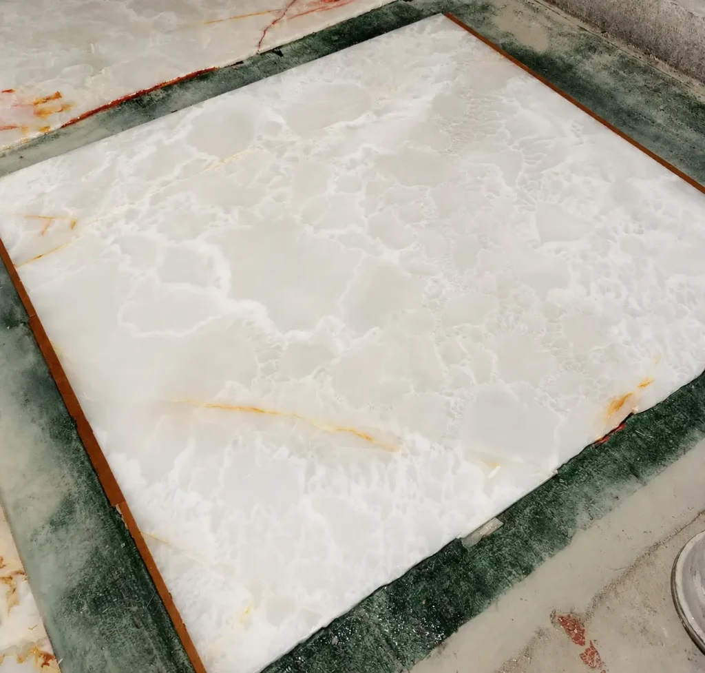 Polished Afghan White Onyx slab in bright white background with soft grey and honey toned natural veins